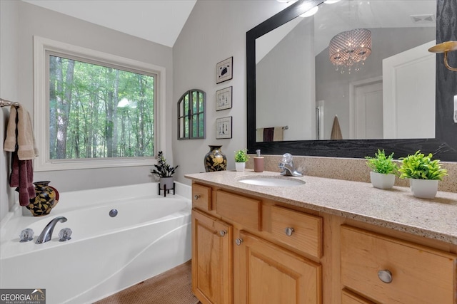 bathroom featuring vanity, vaulted ceiling, a bathing tub, and an inviting chandelier