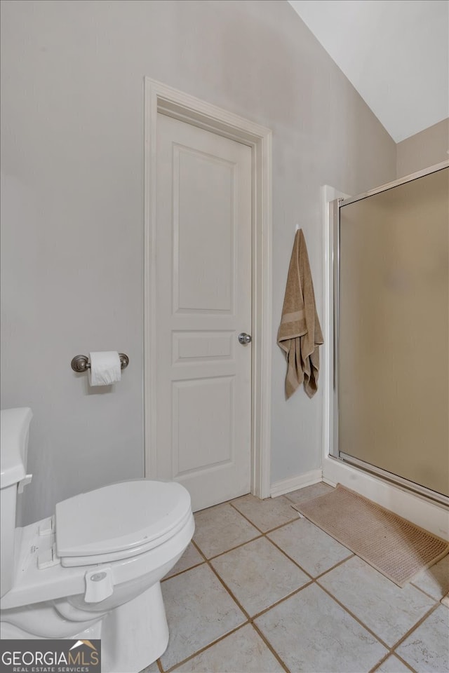 bathroom featuring lofted ceiling, toilet, tile patterned flooring, and a shower with door