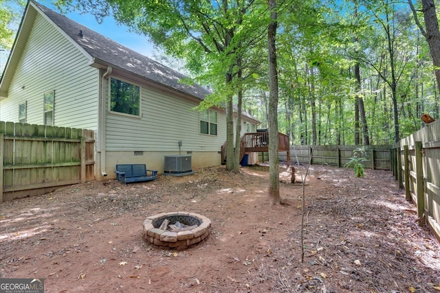 rear view of property with a fire pit, a deck, and central air condition unit