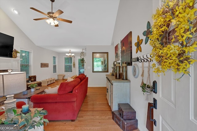 living room with ceiling fan with notable chandelier, vaulted ceiling, and wood-type flooring