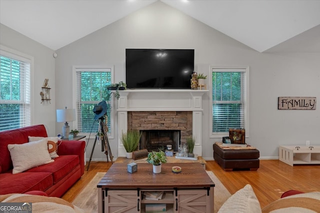 living room featuring lofted ceiling, light hardwood / wood-style flooring, plenty of natural light, and a fireplace