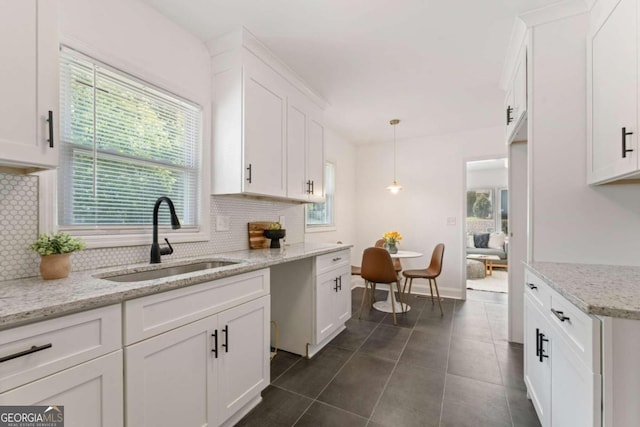 kitchen featuring backsplash, sink, white cabinets, and decorative light fixtures