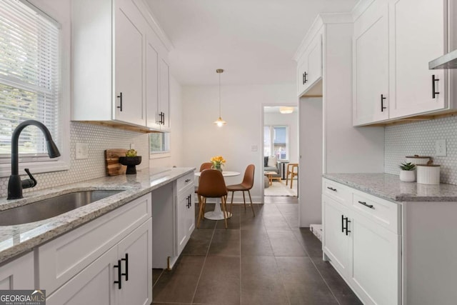 kitchen featuring a wealth of natural light, sink, white cabinetry, and tasteful backsplash