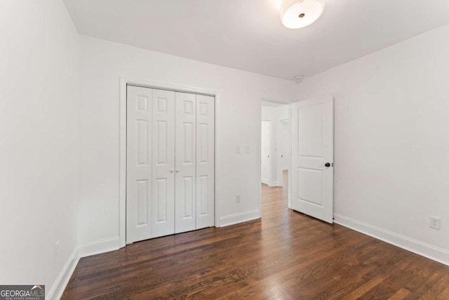 unfurnished bedroom featuring dark wood-type flooring and a closet