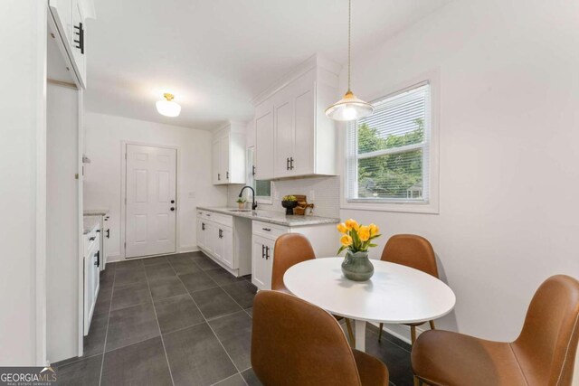 kitchen featuring decorative light fixtures, backsplash, white cabinetry, and sink