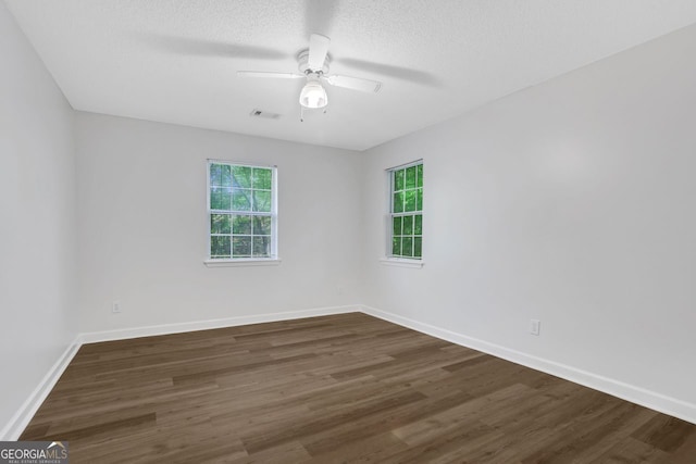 unfurnished room with ceiling fan, plenty of natural light, and dark wood-type flooring