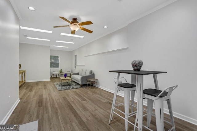 dining space with ornamental molding, wood-type flooring, and ceiling fan