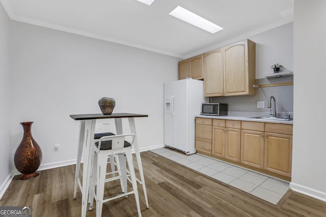 kitchen with white fridge with ice dispenser, light brown cabinetry, light hardwood / wood-style floors, and sink