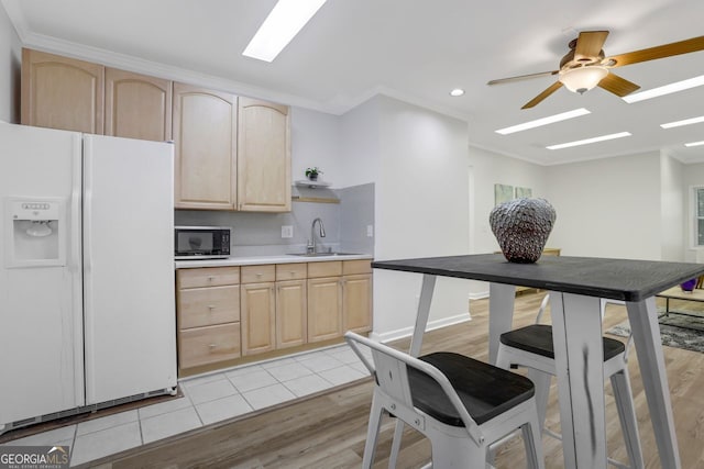 kitchen with white fridge with ice dispenser, sink, light hardwood / wood-style flooring, ceiling fan, and light brown cabinetry