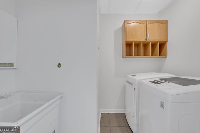 clothes washing area with cabinets, light tile patterned floors, and washing machine and dryer