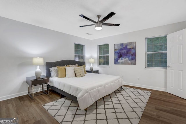 bedroom with ceiling fan, dark hardwood / wood-style floors, and multiple windows