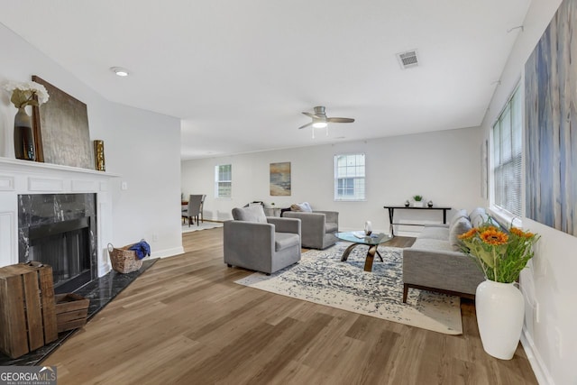 living room with wood-type flooring, ceiling fan, and a fireplace