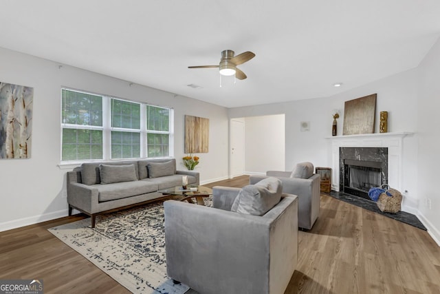 living room with ceiling fan, light wood-type flooring, and a premium fireplace