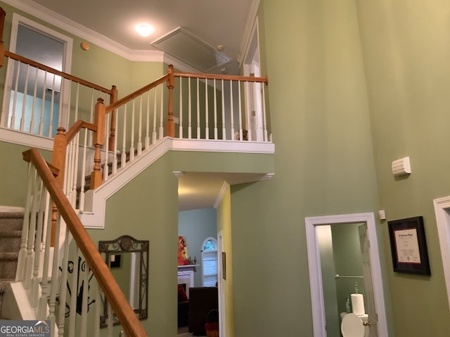 stairs with a towering ceiling and crown molding