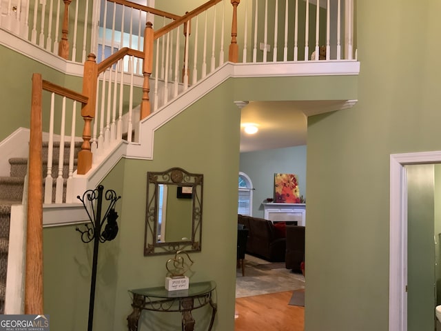 stairs with wood-type flooring and a towering ceiling