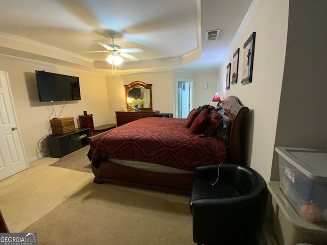 carpeted bedroom with ornamental molding, a tray ceiling, and ceiling fan