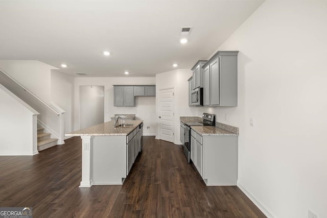 kitchen featuring light stone counters, stainless steel appliances, dark hardwood / wood-style floors, and a kitchen island with sink