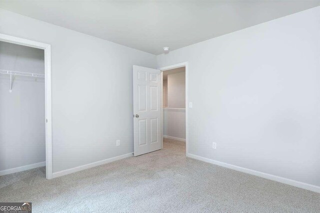 unfurnished bedroom featuring light colored carpet and a closet