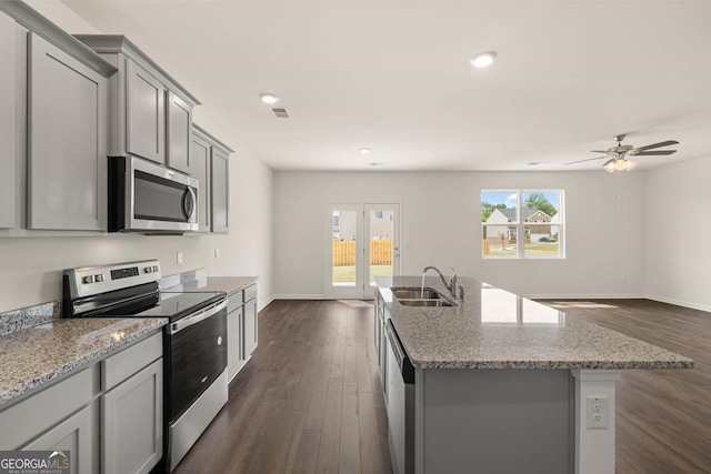 kitchen featuring stainless steel appliances, sink, dark hardwood / wood-style floors, ceiling fan, and a kitchen island with sink