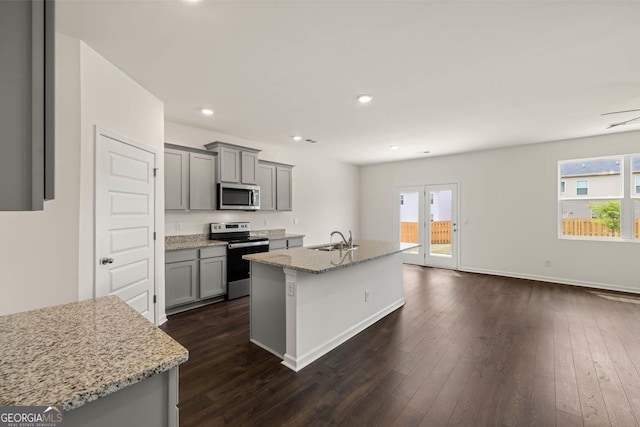 kitchen with a wealth of natural light, stainless steel appliances, gray cabinetry, and a center island with sink