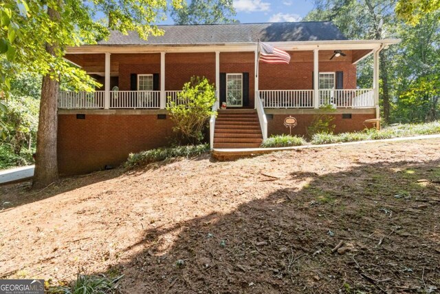 view of front of house with brick siding, crawl space, and a porch