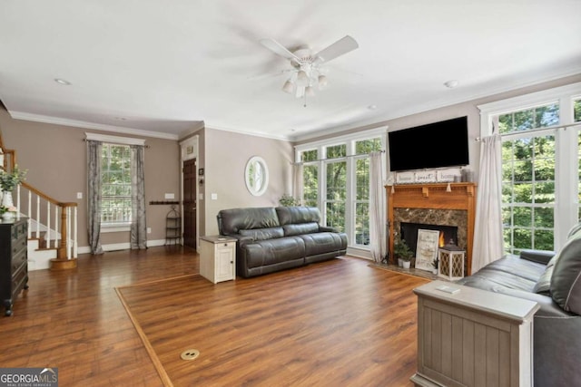 living room with ornamental molding, wood finished floors, a fireplace, baseboards, and stairs