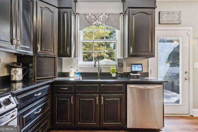 kitchen featuring dark countertops, appliances with stainless steel finishes, wood finished floors, and a sink