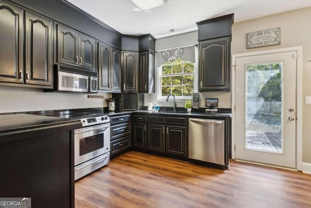 kitchen featuring a sink, dark countertops, appliances with stainless steel finishes, and wood finished floors