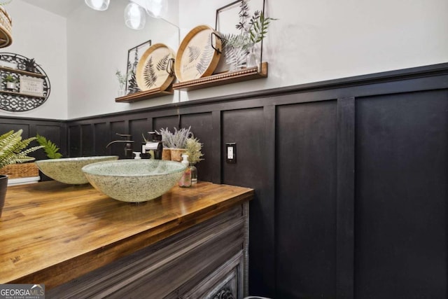 bathroom with a wainscoted wall, vanity, and a decorative wall