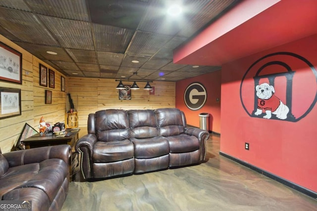 living room with baseboards, wood walls, and finished concrete floors