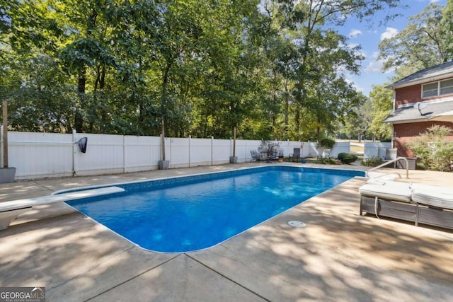 view of pool featuring a diving board, a fenced in pool, a fenced backyard, and a patio area