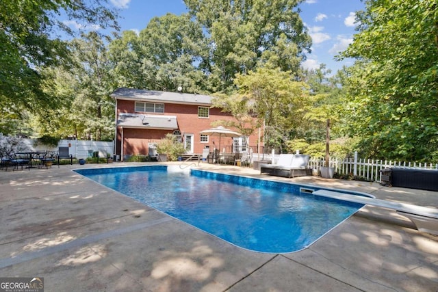 view of swimming pool with a diving board, a patio, and fence