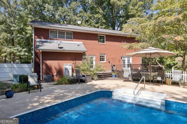 back of property featuring brick siding, fence, central AC, a patio area, and an outdoor pool