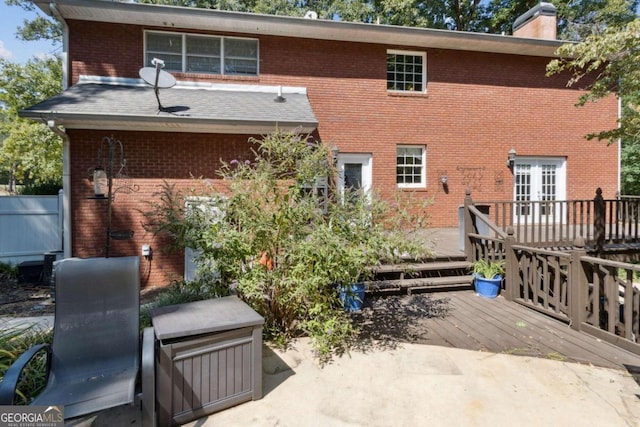 back of house with a wooden deck, brick siding, and a chimney