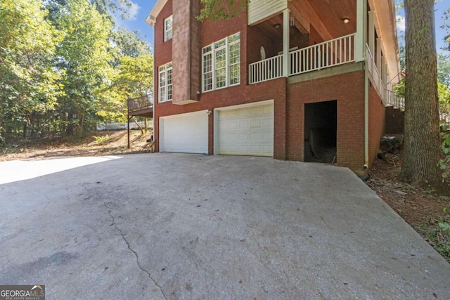 view of side of home with concrete driveway, an attached garage, and brick siding