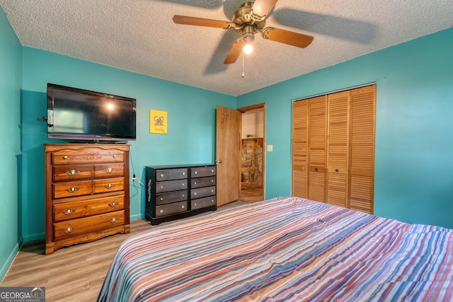 bedroom featuring baseboards, ceiling fan, wood finished floors, a closet, and a textured ceiling