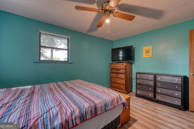 bedroom with a textured ceiling, ceiling fan, and hardwood / wood-style floors