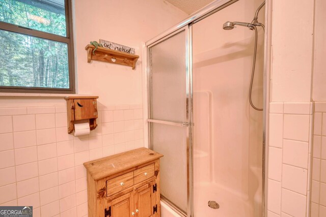 bathroom featuring tile walls and an enclosed shower