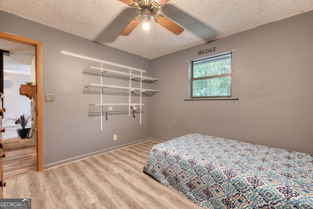 bedroom featuring ceiling fan, hardwood / wood-style flooring, and a textured ceiling