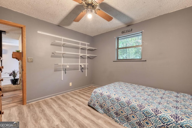 bedroom featuring ceiling fan, a textured ceiling, baseboards, and wood finished floors