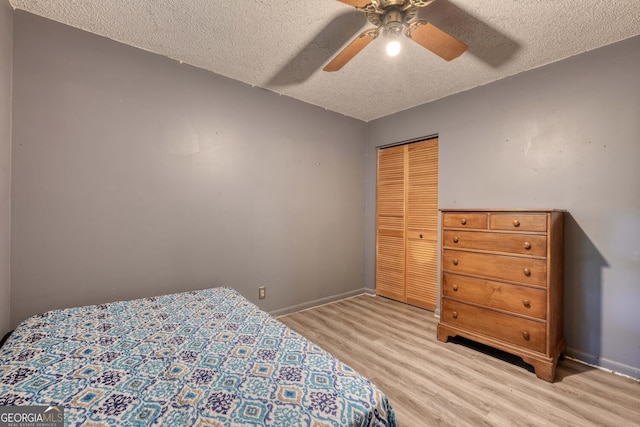 bedroom featuring a closet, a textured ceiling, light wood-type flooring, and baseboards