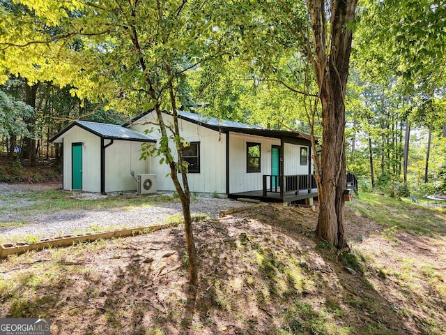 view of front of house featuring ac unit, metal roof, and a forest view