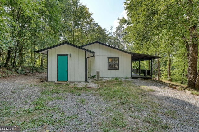 view of outdoor structure featuring central air condition unit, an attached carport, and driveway