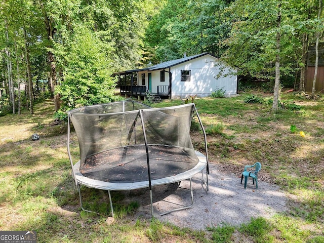 view of yard with a trampoline and a wooden deck