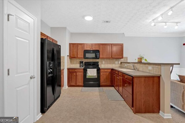 kitchen with a textured ceiling, black appliances, kitchen peninsula, sink, and decorative backsplash