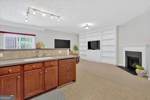 kitchen featuring built in shelves, light colored carpet, sink, tasteful backsplash, and a textured ceiling