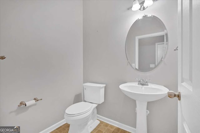 half bath featuring toilet and baseboards