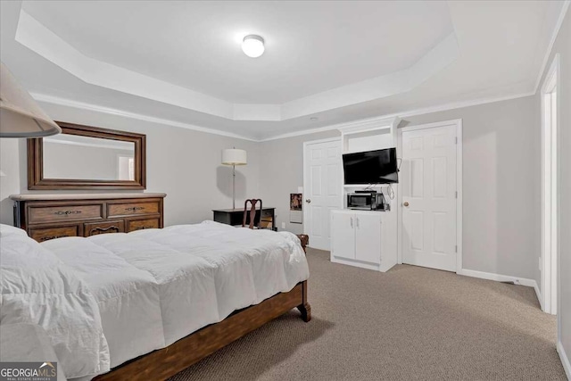 carpeted bedroom with a tray ceiling and ornamental molding