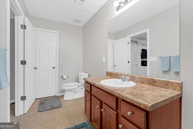 bathroom featuring vanity, toilet, a textured ceiling, and tile patterned flooring