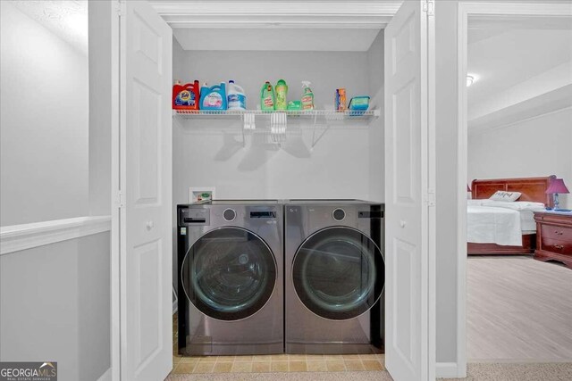 clothes washing area with washer and clothes dryer and light hardwood / wood-style floors